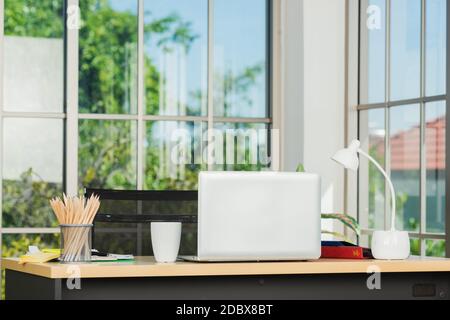 Back laptop computer putting on working desk, Workplace with notebook laptop on the table, Home interior or office background Stock Photo