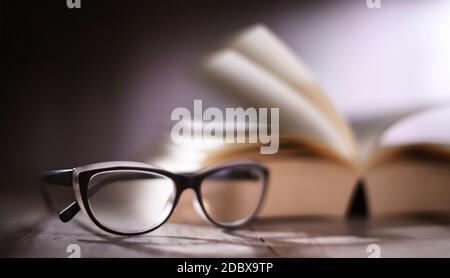 Composition with glasses and open book on the table. Stock Photo