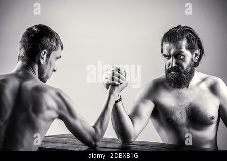 Arms wrestling thin hand, big strong arm in studio. Two man's hands clasped arm wrestling, strong and weak, unequal match. Black and white