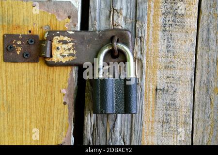 Old padlock hanging on a wooden shabby door Stock Photo