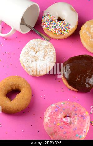 A bunch of donuts over a hot pink background with a coffee cup. Stock Photo