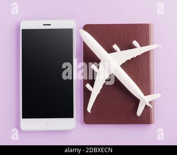 World Tourism Day, Top view flat lay of minimal toy model plane, airplane on passport and mobile smartphone blank screen, studio shot isolated on a pu Stock Photo