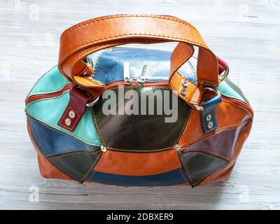 top view of handcrafted patchwork leather travel bag on gray wooden table Stock Photo