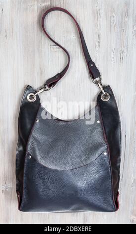 handcrafted gray leather handbag with big pocket on gray wooden table Stock Photo