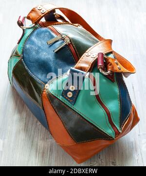 handmade patchwork leather travel bag on gray wooden board Stock Photo