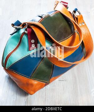 handcrafted patchwork leather travel bag on gray wooden table Stock Photo