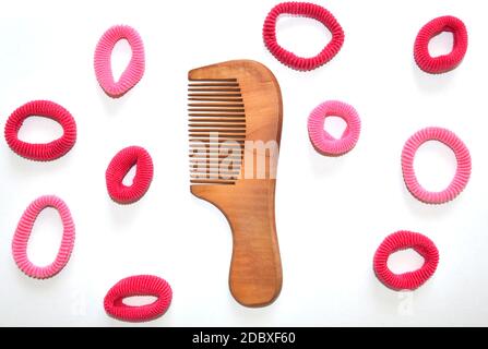 Wooden comb with bright pink hair scrunchies isolated on white Stock Photo