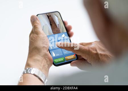 Elder Using Home Heating Control And Alarm Automation Stock Photo