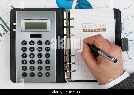 Diary, calculator,hand and pen  on a background of diagrams and graphs Stock Photo