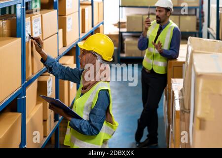 Islam Muslim female warehouse worker do logistic inventory route with his manager use walky talky inbackground in warehouse distribution. For business Stock Photo