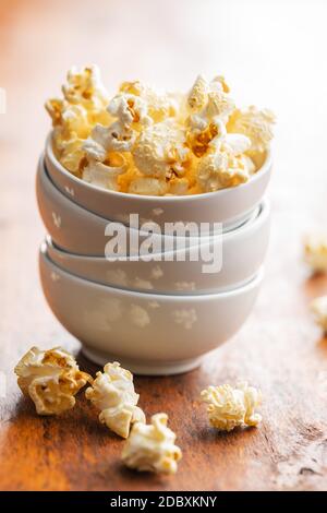 Sweet tasty popcorn in bowl on wooden table.