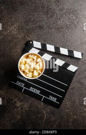 Sweet popcorn in cup and clappeboard on black table. Top view. Stock Photo