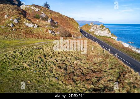 The eastern coast of Northern Ireland and Causeway Coastal Route with a cyclist. One of the most scenic coastal roads in Europe. Aerial view in winter