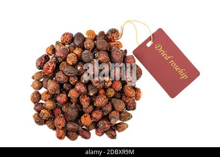 Dried rose hips with a tag isolated on a white background. The inscription on the tag Dried rose hips. Alternative medicine. Stock Photo