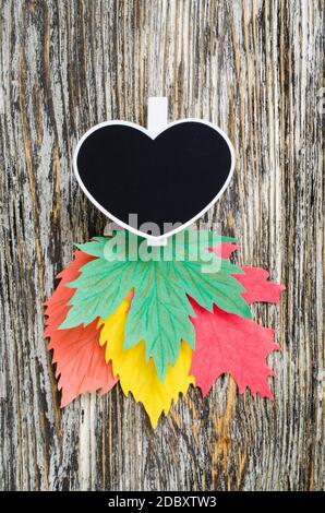 Autumn background: chalk board in heart shaped with colorful paper leaves on vintage textured wooden background. Autumn concept. Fall season banner te Stock Photo