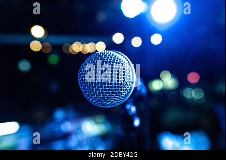 the vocalist's microphone stands on stage in the light of multicolored spotlights Stock Photo