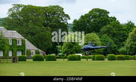 Helicopter flying (takeoff or arrival) at country house hotel (luxury transport charter service) - Devonshire Arms, Bolton Abbey, Yorkshire Dales, UK. Stock Photo