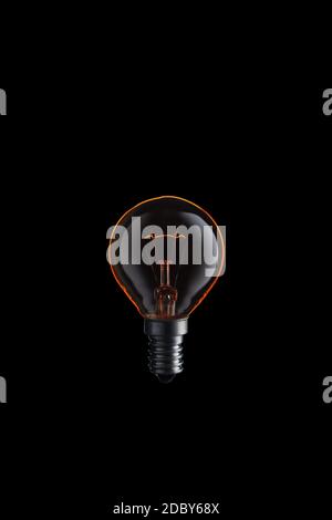 Burning Light bulb on black background. Stock Photo