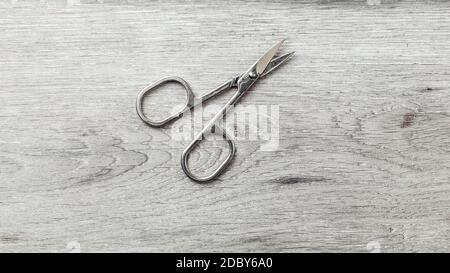 Manicure cuticle scissors on laminate flooring that looks like white wood table. Stock Photo