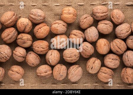 Unshelled walnut lying on sackcloth Stock Photo