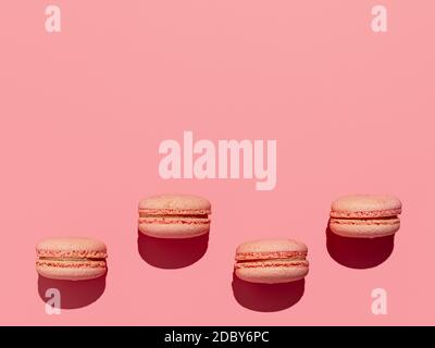 Pink macarons with copy space. Row of perfect french macarons or macaroons on pink background. Top view or flat lay. Hard light Stock Photo
