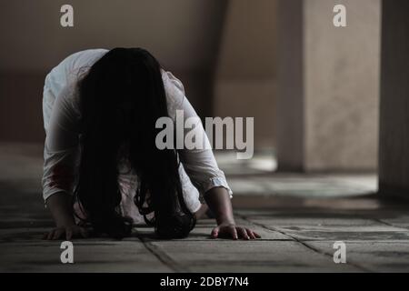 Girl zombie in blood. Asian Woman ghost with blood. Horror scary fear in dark house creepy crawling move slowly creeping out. Hair covering face her e Stock Photo