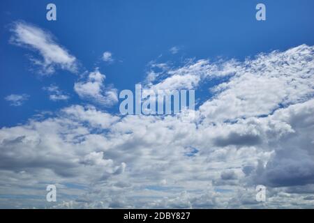 The blue sky dotted with cumulus clouds in the light of the summer sun Stock Photo