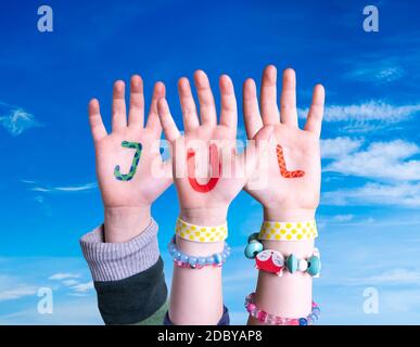 Children Hands Building Colorful Swedish Word Jul Means Christmas. Blue Sky As Background Stock Photo