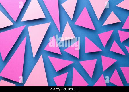 Abstract composition with pink triangular paper shapes over blue background. Top view Stock Photo