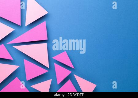 Pink triangular shapes in minimal creative style. Paper composition on blue background for presentations. Top view. Copy space Stock Photo