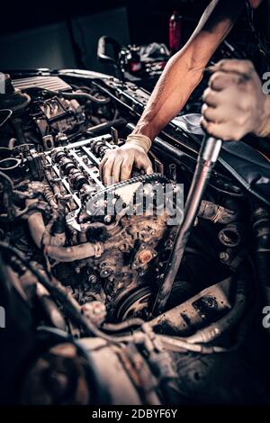 Mechanic working in a car under the hood, repairing an engine Stock Photo