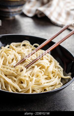 Cooked udon noodles. Traditional Japanese noodles in plate on black table. Stock Photo