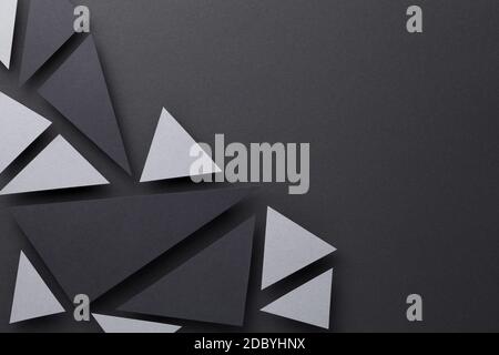 Abstract composition over black paper background with gray and black triangular shapes. Minimal style. Copy space. Top view Stock Photo
