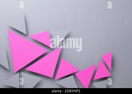 Minimal geometric composition over gray paper background with pink and gray triangular shapes. Copy space. Top view Stock Photo