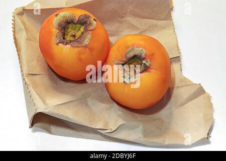 Persimmon Fruit. Isolated. Copy Space. Lotus fruit laid on a brown paper bag. White background . Stock Image. Stock Photo