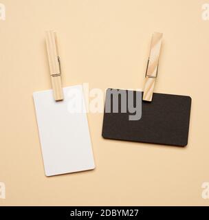 white and black paper rectangular business cards with wooden clothespins on beige tone, copy space Stock Photo
