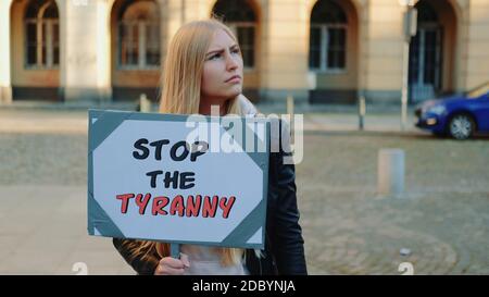 Young woman calling to stop the tyranny by holding steamer. Protest walk in the city center. Stock Photo
