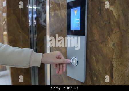 The girl calls the Elevator, ride the Elevator in the office, shopping center or business center to the second floor. The hand presses a button on the Stock Photo