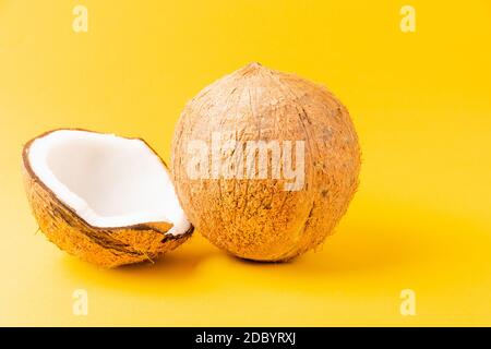 Happy coconuts day concept, Fresh full coconut with half coconut, studio shot isolated on yellow background Stock Photo