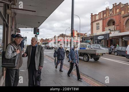 Two older men stand and talk outside a shop in the main street of  Haberfield, New South Wales, Australia Stock Photo