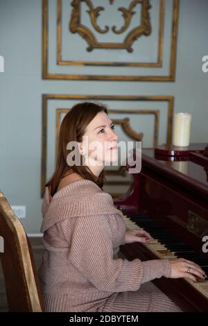 A woman plays an old piano. European-looking brunette Stock Photo
