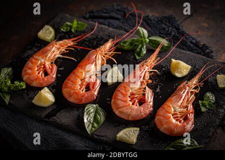 Raw fresh prawns on black slate board, uncooked and unshelled Stock Photo