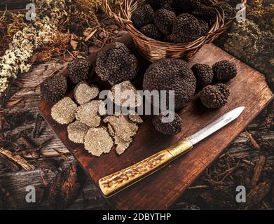 Black truffle with knife over rustic wooden  cutting board Stock Photo