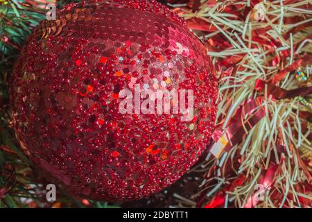 Christmas red bauble with glitter brooches and sparkles on tinsel decorations. Stock Photo