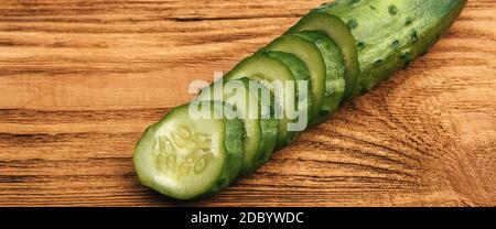Cucumber sliced lies on a wooden table. Next to the place for the inscription. Background, layout, mockup. Stock Photo
