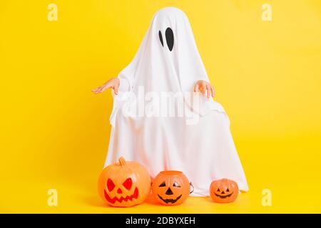 Funny Halloween Kid Concept, full body of a little cute child with white dressed costume halloween ghost scary he holding orange pumpkin ghost, studio Stock Photo