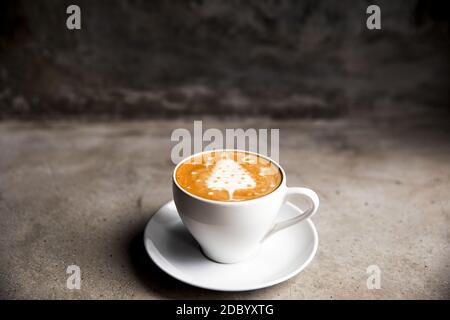 Tasty cappuccino with Christmas tree latte art on grey concrete background. Holiday concept. Stock Photo