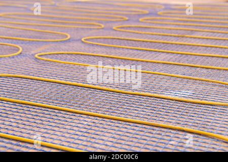 Electric underfloor heating, yellow cable on cement floor. Repair and construction, the concept of a cozy warm home Stock Photo
