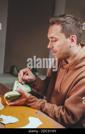 Shoemaker drawing a pattern on the shoe model. Stock Photo