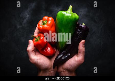 Hands with different bell peppers. View from above Stock Photo